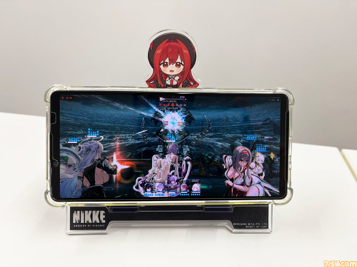 famitsu's tweet photo. 『NIKKE』4周年特集号の“グッズ付き限定版”が予約受付開始！【週刊ファミ通】
https://t.co/ymwH42IqSE

ニケに“見守られる”特製スマホスタンドと、3周年特集号の表紙イラストをあしらったアクリルパネルが同梱。イラストはいずれも描き下ろし。
4周年特集号は、2026年11月5日発売予定。 https://t.co/PRh5oPT7Pg