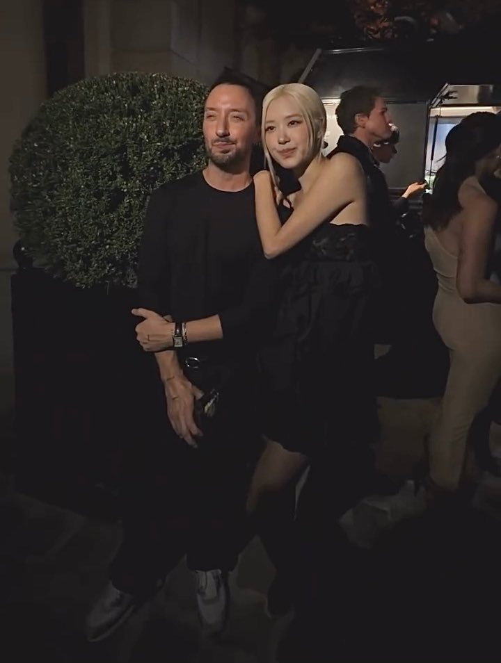 A slightly blurry nighttime photograph of a man and a blonde woman posing closely together at what appears to be a social event or party.