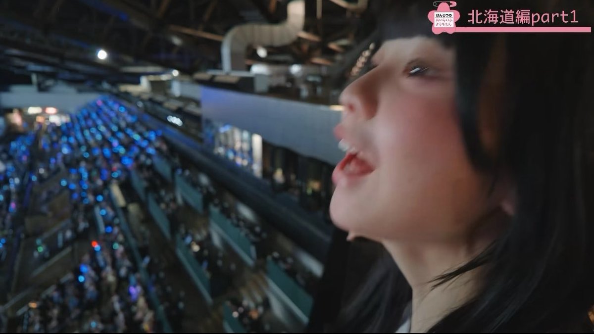 Profile shot of a young woman singing at a concert with blue light sticks visible in the audience below; Japanese text overlay reads "ほんでの北海道 part 1" (Hokkaido Part 1).