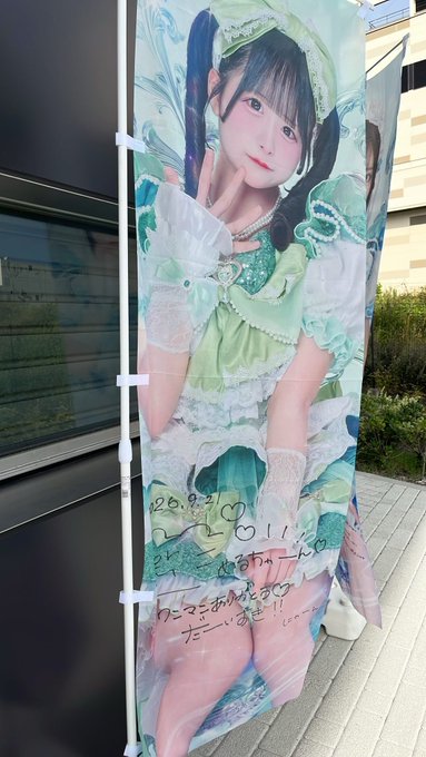An outdoor promotional banner features a Japanese idol in a green and white frilly outfit with handwritten messages dated 2024.9.1.