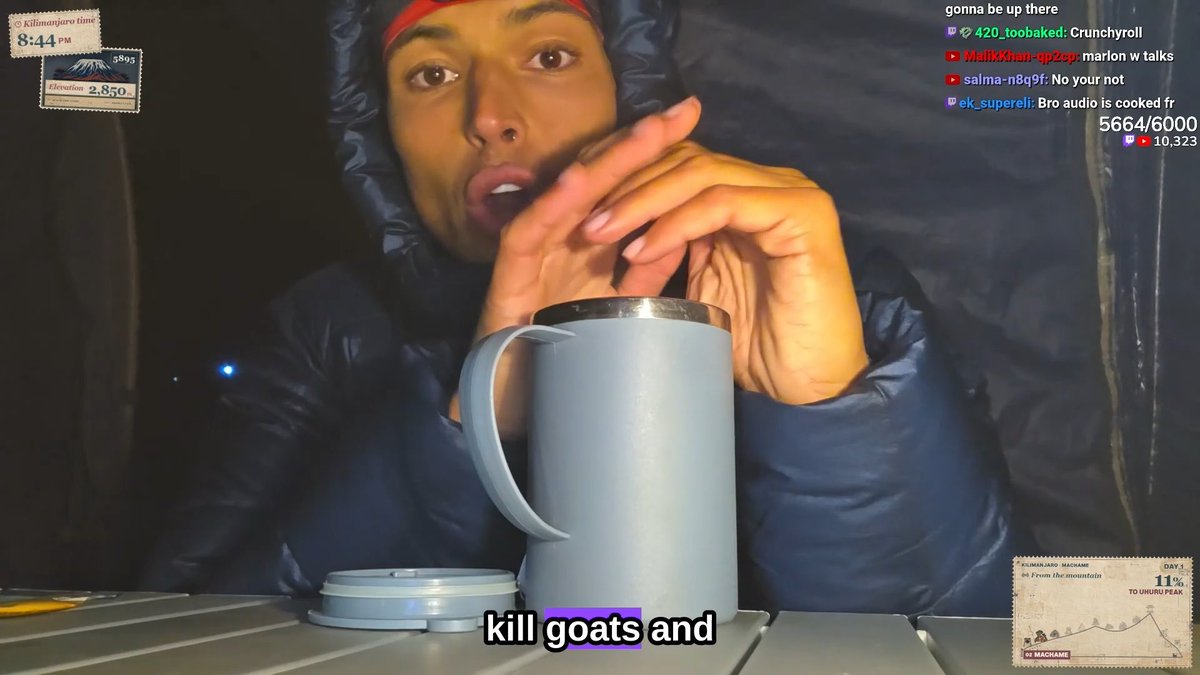 A person bundled in a blue hooded jacket sits beside a tall insulated mug at night, with subtitles reading "kill goats and" appearing on screen. The livestream interface shows the time "8:44 PM" along with chat messages and a Kilimanjaro elevation tracker reading "2,850," tying the visual to the discussion about life in Africa.