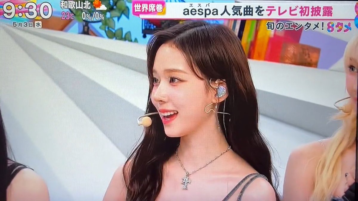 A Japanese television broadcast screenshot shows a member of K-pop group aespa performing, with on-screen text reading 'aespa人気曲をテレビ初披露' (TV debut of aespa's popular song) at 9:30 AM.
