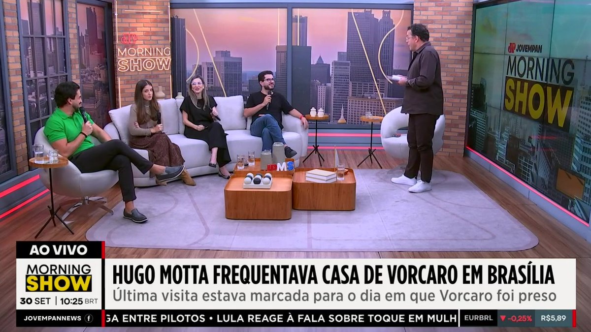 The image shows a live broadcast of Jovem Pan's "Morning Show" with the headline "HUGO MOTTA FREQÜENTAVA CASA DE VORCARO EM BRASÍLIA" (Hugo Motta used to frequent Vorcaro's house in Brasília), featuring hosts discussing the political news alongside the ticker mentioning R$5.89 and a 0.25% drop in EURBL.