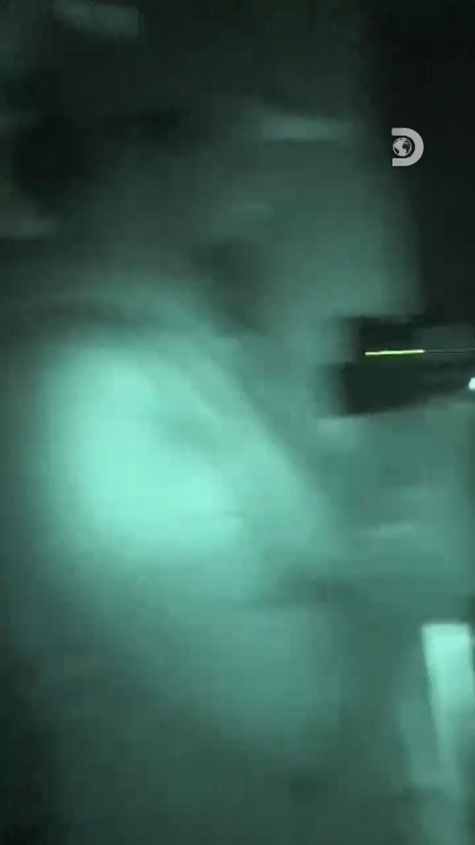 A ghostly figure emerges from green-tinted mist in a dark, eerie setting, with the Discovery channel logo visible in the upper right corner, evoking the paranormal atmosphere of a Las Vegas escape room featured in the new season of #GhostAdventures premiering on Discovery.