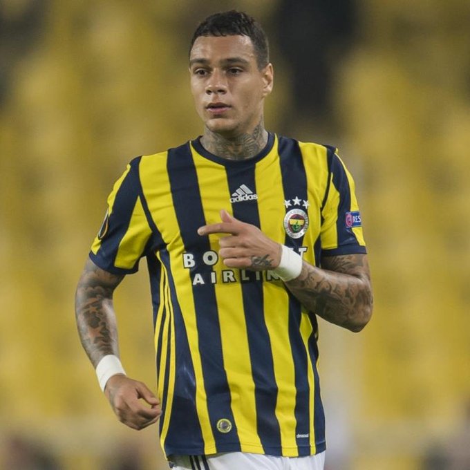A tattooed athlete wears a yellow and navy striped Fenerbahçe soccer jersey featuring the "Boyd" Airlines sponsor logo, with one finger pointed across his chest against a blurred stadium background.