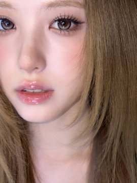 A close-up beauty shot of a woman with light brown hair, glossy pink lips, and detailed eye makeup.