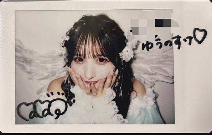 A polaroid-style photo of a young woman with dark hair and white floral accessories, framed by handwritten Japanese text 'ゆうのすて♡' and cloud doodles.