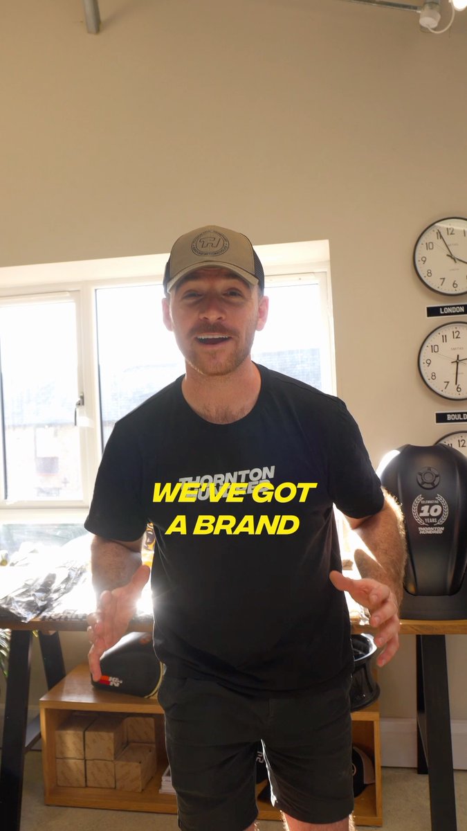 A man wearing a cap and a black "THORNTON" t-shirt stands indoors with yellow text overlay reading "WE'VE GOT A BRAND".