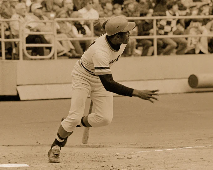 Baseball player in motion during a game, wearing a helmet and uniform.