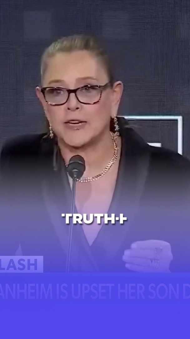 A news broadcast screenshot of a blonde woman wearing glasses and a necklace speaking at a podium with a microphone, with the text 'TRUTH' overlaid and partial text below reading 'ANHEIM IS UPSET HER SON D...'.