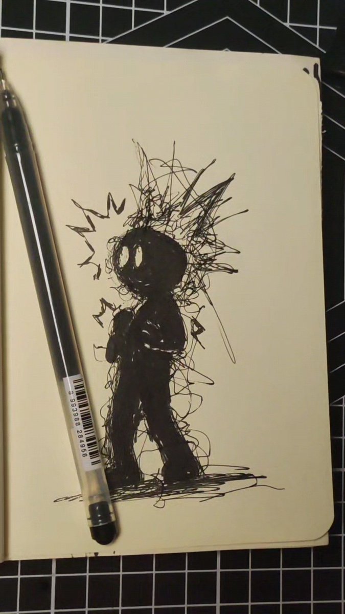 A pen rests on top of a sketchbook page displaying a rough ink drawing of a dark, spiky-haired figure with a scribbled aura on a cutting mat.