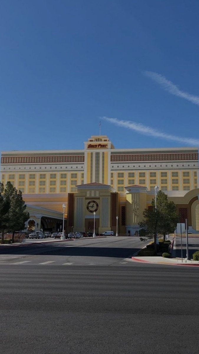 An exterior view of the South Point hotel and casino building under a clear blue sky with a few wispy clouds.