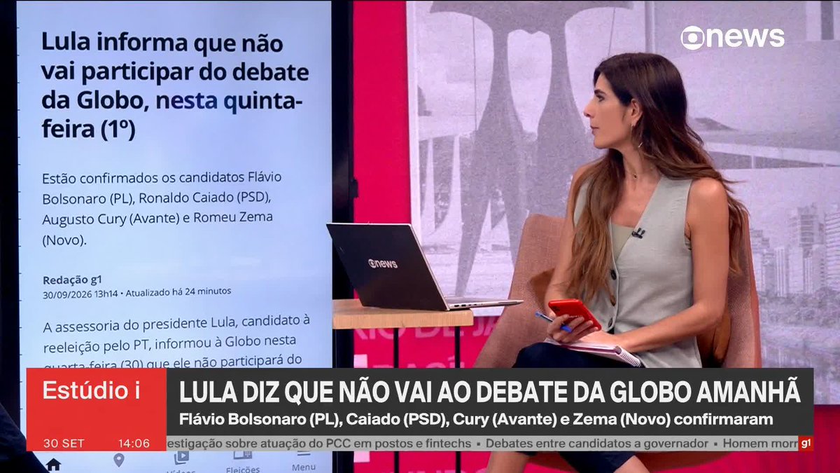 A Globo News broadcast featuring a female anchor at her laptop with the headline 'Lula informa que não vai participar do debate da Globo, nesta quinta-feira (1°)' and chyron 'LULA DIZ QUE NÃO VAI AO DEBATE DA GLOBO AMANHÃ', listing candidates Flávio Bolsonaro (PL), Caiado (PSD), Cury (Avante) and Zema (Novo).