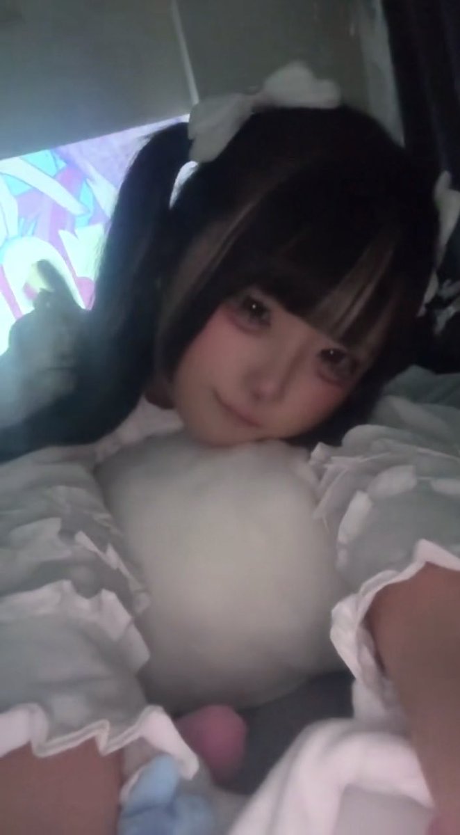 A person wearing a maid outfit with white frilly sleeves and a white headpiece leans forward with a playful pout.
