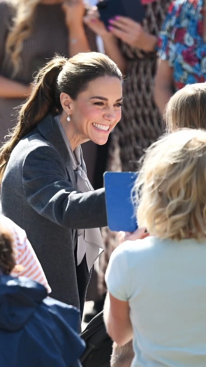 Princess Kate beams warmly as she greets fans during her trip to Pulborough, West Sussex, where she celebrated the 50th anniversary of the local minibus service by sharing a sweet interaction with a young girl holding a blue folder.