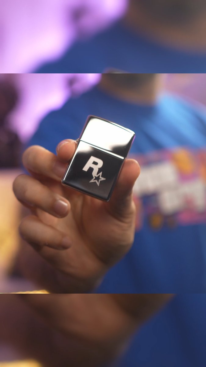 A hand holding up a silver Zippo-style lighter engraved with the Rockstar Games 'R★' logo against a blurred background.