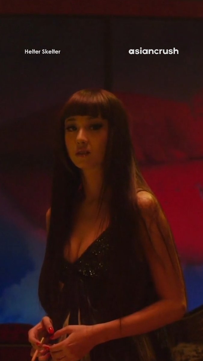 A woman with long dark hair and bangs in a black sparkly top is shown with text 'Helter Skelter' and 'asiancrush' at the top.