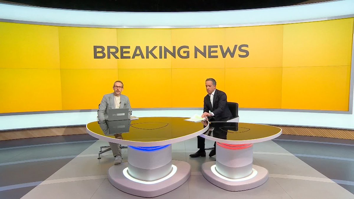 Two news anchors sit at a sleek glass desk with "sky sports" branding in a studio featuring a large yellow "BREAKING NEWS" backdrop, delivering breaking coverage of Etihad Airways potentially taking legal action against the Premier League over their Manchester City sponsorship.
