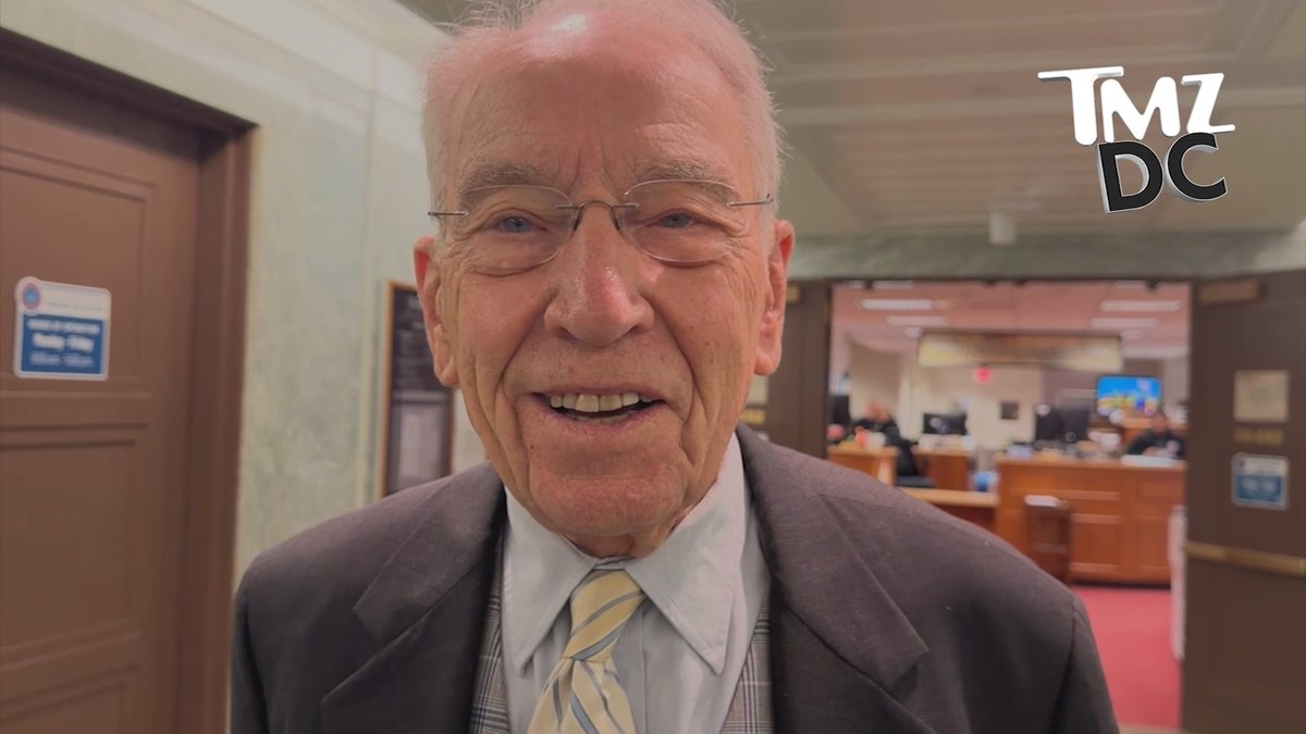 Senator Chuck Grassley smiles broadly in a government building hallway, wearing a dark suit with a yellow and blue striped tie, while the TMZ DC logo appears in the corner of the frame.