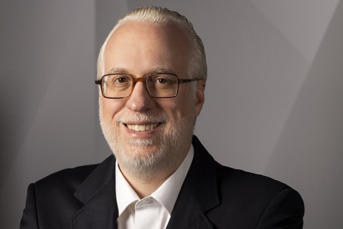 A professional headshot of a smiling, balding man with glasses and a gray beard, wearing a dark suit and white shirt against a gray background. The image accompanies an article featuring Marcelo Portugal Gouvêa, an opposition candidate for the São Paulo presidency, who is pictured as the subject of the political news story.