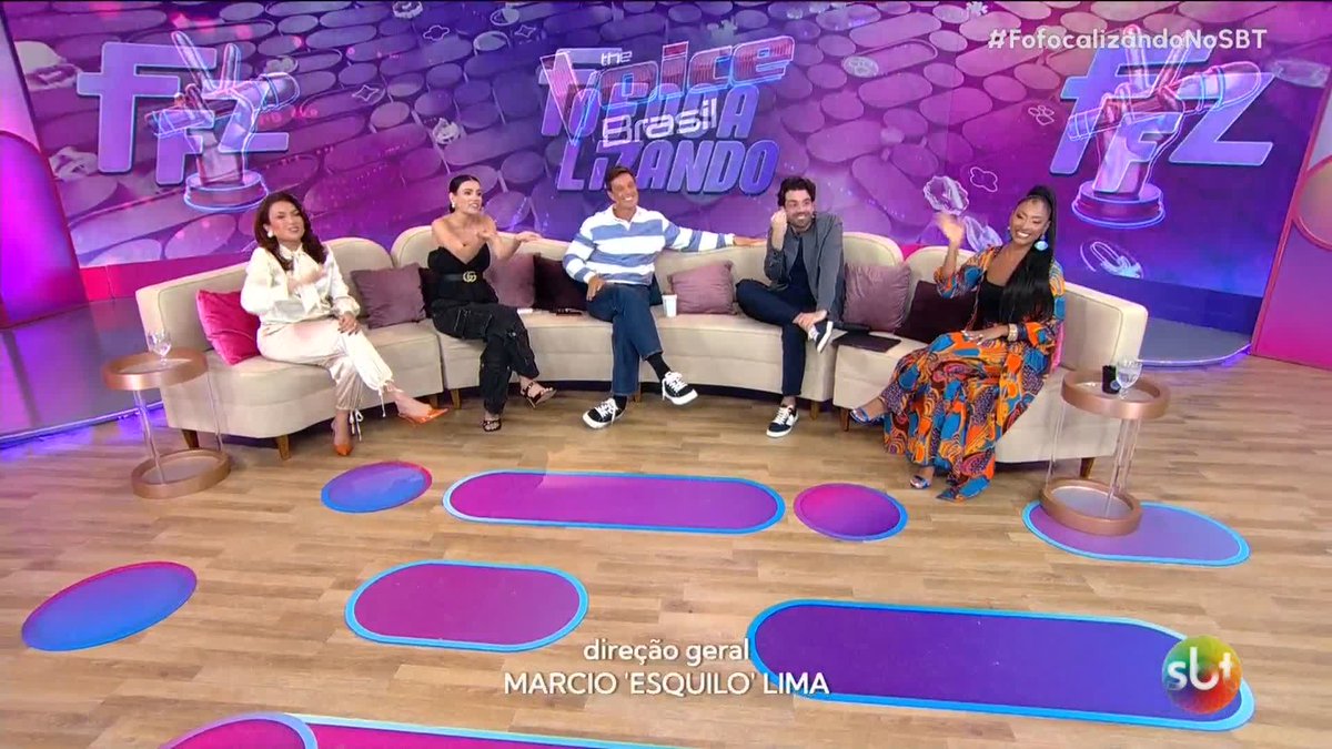 A scene from a Brazilian TV show called 'The Noite com Danilo Gentili' on SBT (as indicated by the 'Fz' logo and 'direção geral MÁRCIO "ESQUILO" LIMA' caption), featuring five people sitting on a couch on a purple-lit set.