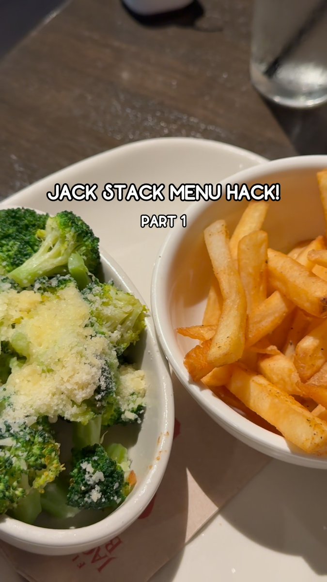 Two white bowls are shown on a restaurant table, one containing broccoli topped with cheese and the other filled with French fries, with the text 'JACK STACK MENU HACK! PART 1' overlaid.