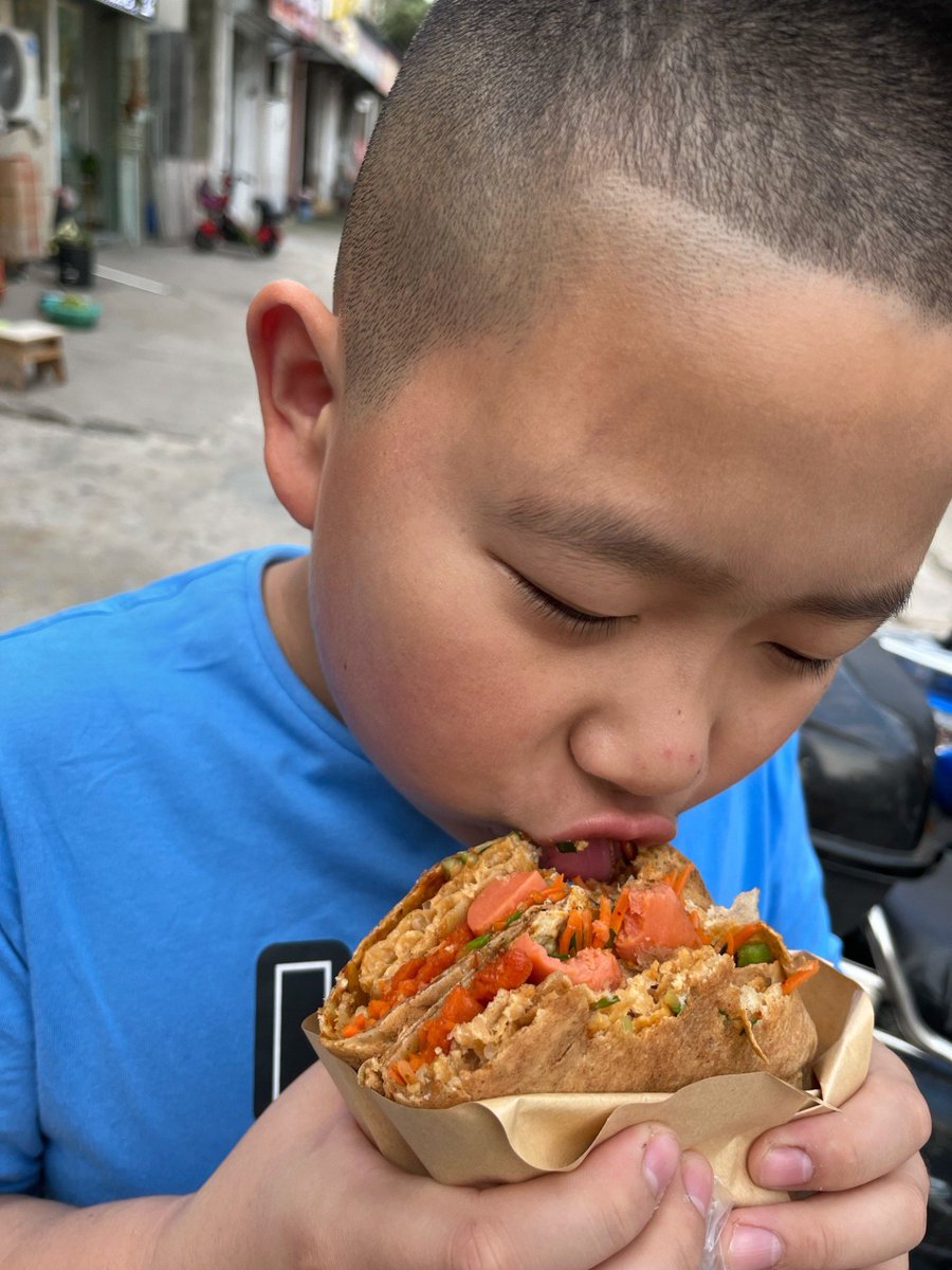 krix_2995oz's tweet photo. Just now, I watched a curious street snack stall—kids gathered around, their faces lit up as they watch the cook skillfully use a bamboo stick to dip food into the spicy sauce. A chubby little boy even stood on tiptoe, making a little sound of sucking his belly in anticipation! https://t.co/GvMrjLOWiI