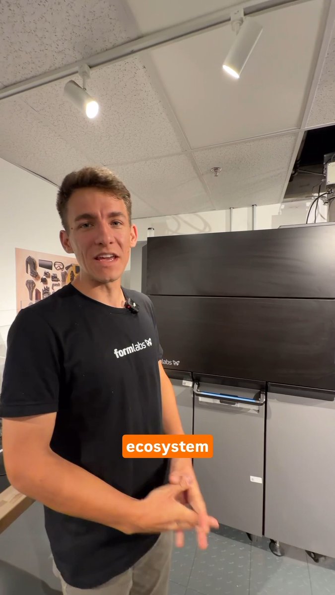 A young man wearing a black 'formlabs' t-shirt stands in front of large industrial equipment with the word 'ecosystem' displayed in an orange text box.