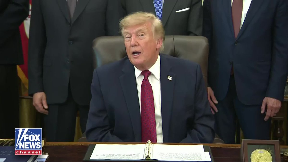 A man in a dark suit and red tie, seated at a desk with documents and a presidential seal, speaks to the camera while other men in suits stand behind him, with a Fox News Channel logo in the bottom left corner. The image accompanies President Trump's claim that the recent GOP midterm convention drew 107 million views, surpassing the NFL's 25 million.