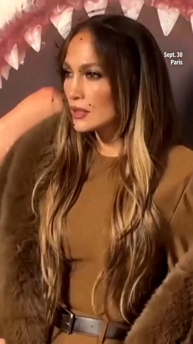 Jennifer Lopez with long brunette hair posing at the Stella McCartney Womenswear Spring/Summer 2027 show in Paris on Sept. 30, wearing a tan top, brown belt, and fur coat.