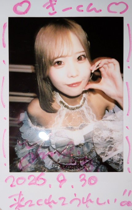 A Polaroid-style photo of a young woman in an elegant dress making a small heart gesture with her fingers, with pink handwritten Japanese text including a date "2026.9.30" at the bottom.