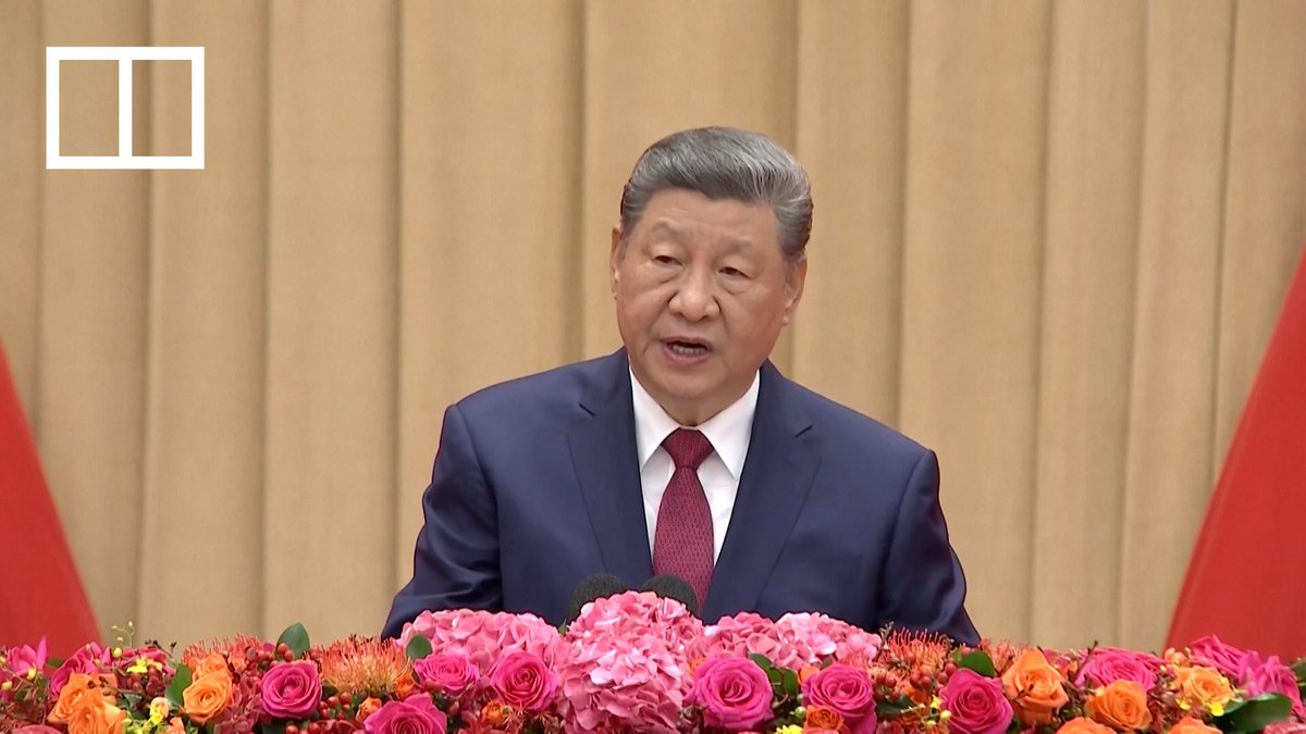 Chinese President Xi Jinping addresses the nation in front of a floral arrangement, projecting a message of confidence as described in the accompanying post. A white box with two vertical segments is visible in the upper left corner of the image.