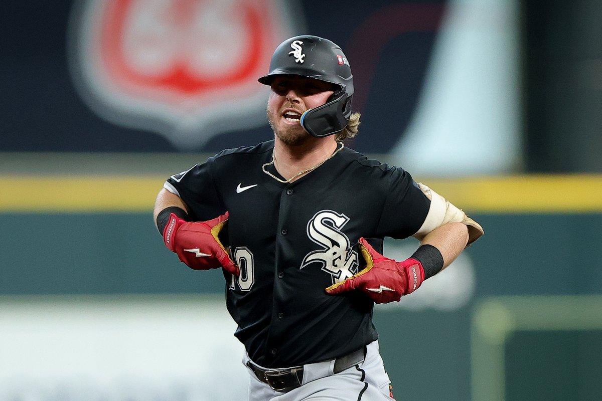 A Chicago White Sox baseball player in a black jersey and red Franklin batting gloves yells in celebration on the field.