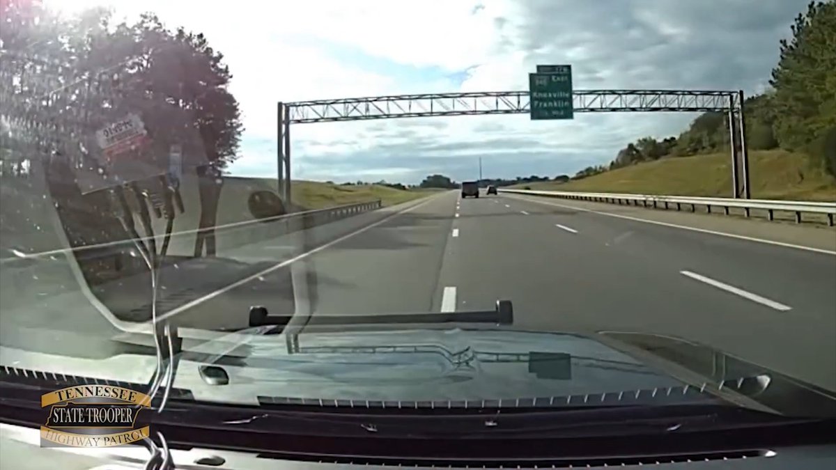 A dashcam image from a Tennessee State Trooper vehicle traveling on Interstate 40, with a green highway exit sign visible ahead indicating Knoxville and Franklin, capturing the moments before a wrong-way driver collided head-on with the patrol car.