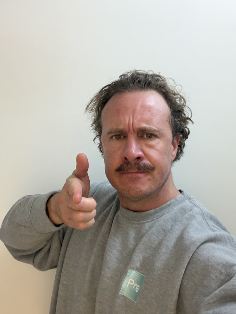bubs's tweet photo. Then I needed to create the characters sheets for visual reference. I gaveAstra a couple photos of my face and one of Rick Grimes and a an outfit I found. 

"Now I need to create a character sheet for the man. Here are detailed photos of his face. His clothing should be post apocalyptic.. also attached a reference image for the jacket and hood. Reference photo of a man with a beard and blood on his face for beard and dirty face inspiration. Bring that facial hairstyle and facial texture to the man with high res photo pointing a fingure gun and use his exact facial features."