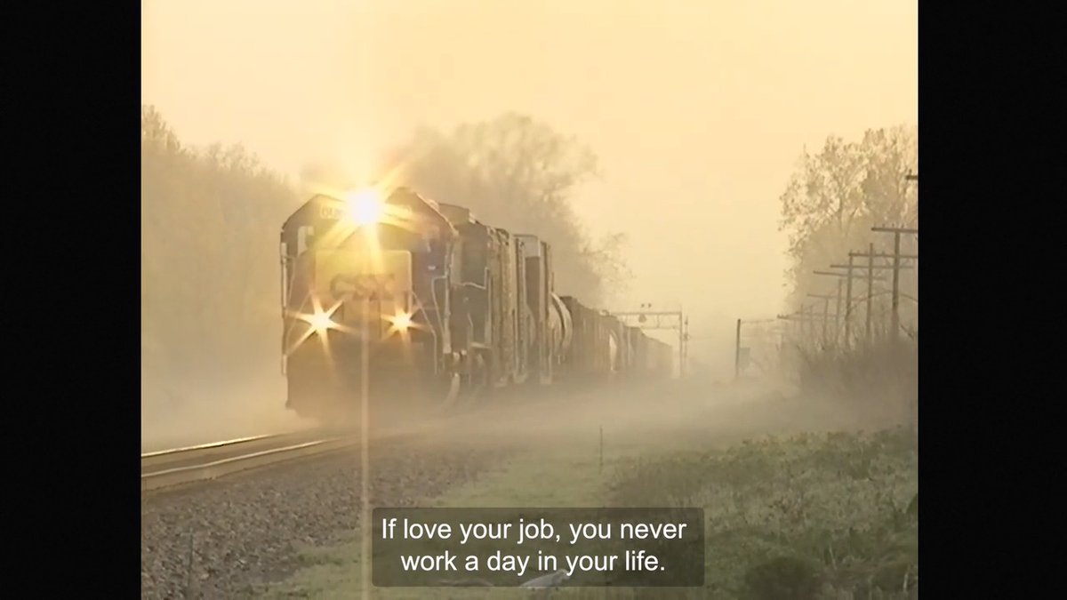 A train with bright headlights moving through a misty, sunlit landscape, captioned with the quote 'If love your job, you never work a day in your life.'