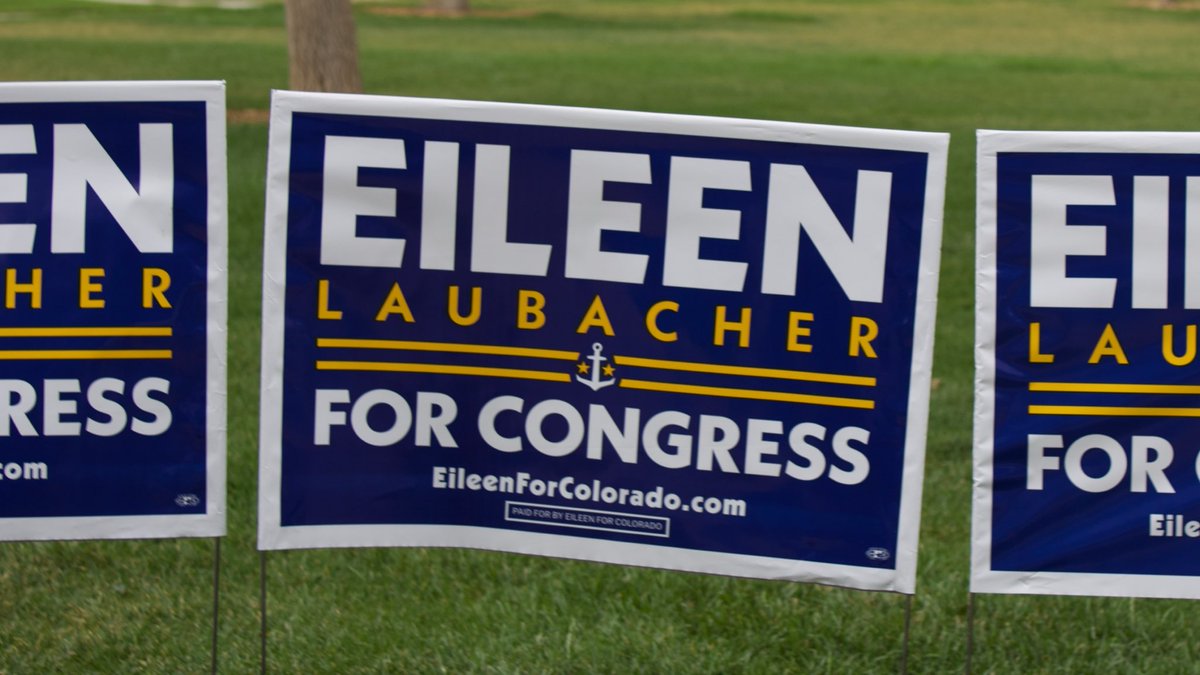 Three navy blue political yard signs on grass reading 'EILEEN LAUBACHER FOR CONGRESS' with 'EileenForColorado.com' and 'PAID FOR BY EILEEN FOR COLORADO'.