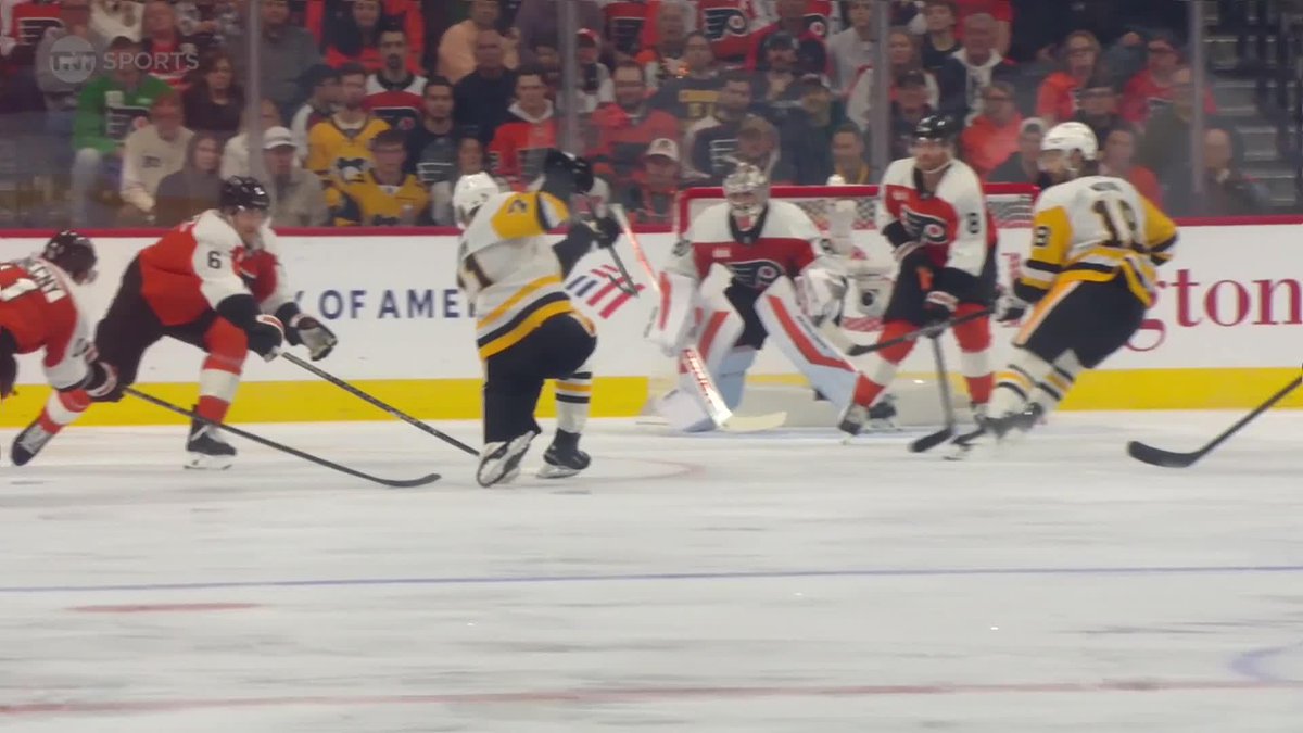 Pittsburgh Penguins player #71 (Evgeni Malkin) winds up for a powerful shot on the power play, with the puck visible in mid-flight toward the Philadelphia Flyers' goal during an NHL game broadcast on TNT Sports. The Flyers' goaltender and defenders are positioned in the net area as the shot approaches, capturing the moment just before the goal referenced in the caption.