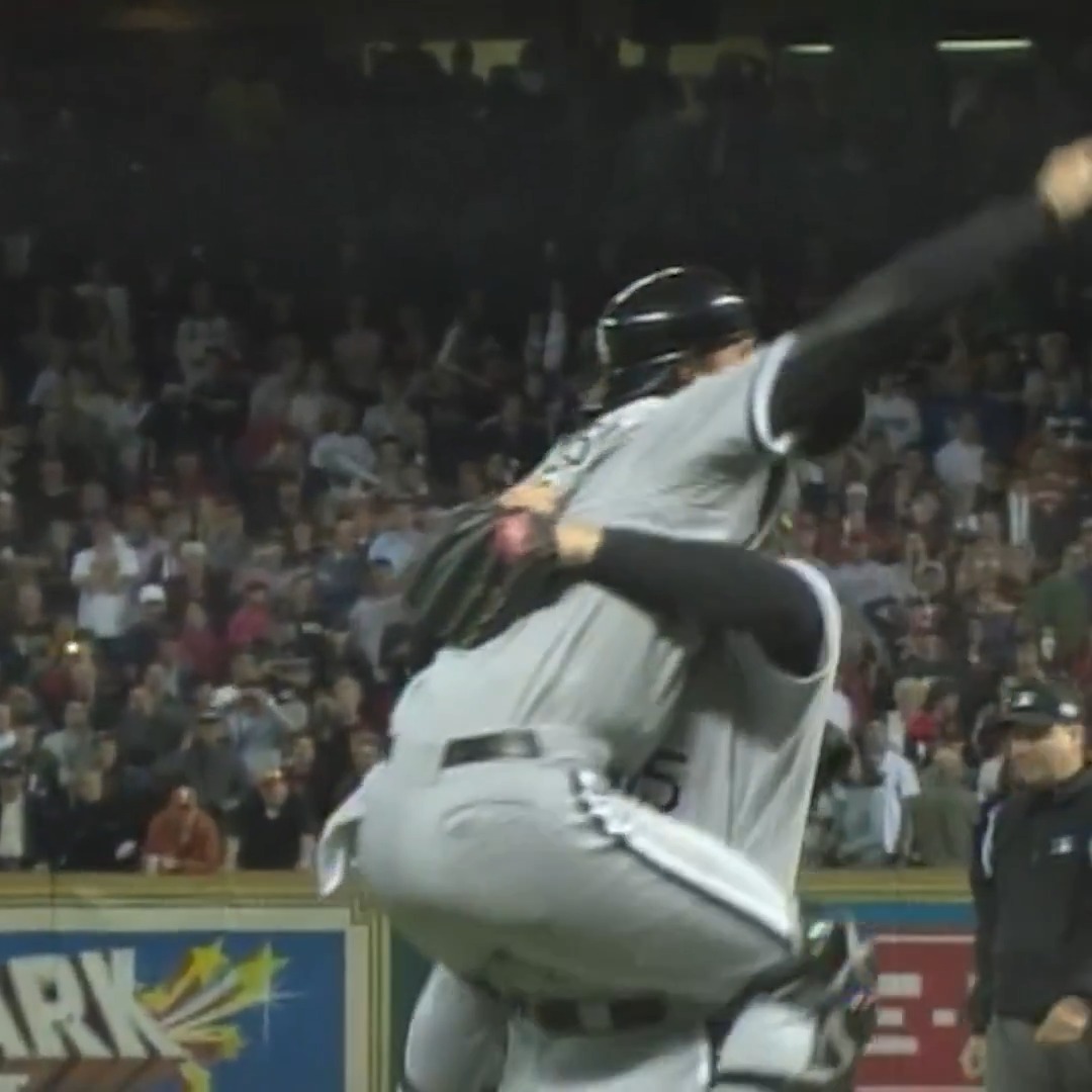 Two White Sox players in gray uniforms embrace in celebration, with one being lifted off the ground, while a jubilant crowd watches from the stands behind them; the context suggests this marks a postseason victory in Houston, connecting to the team's last such series win in 2005.
