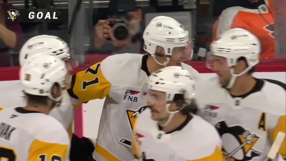 Pittsburgh Penguins players, including one wearing jersey #17, celebrate a goal on the ice as shown by the "GOAL" graphic in the upper left corner. The Penguins logo is also visible, matching the post about "Geno" (Evgeni Malkin) scoring a one-timer on the power play.