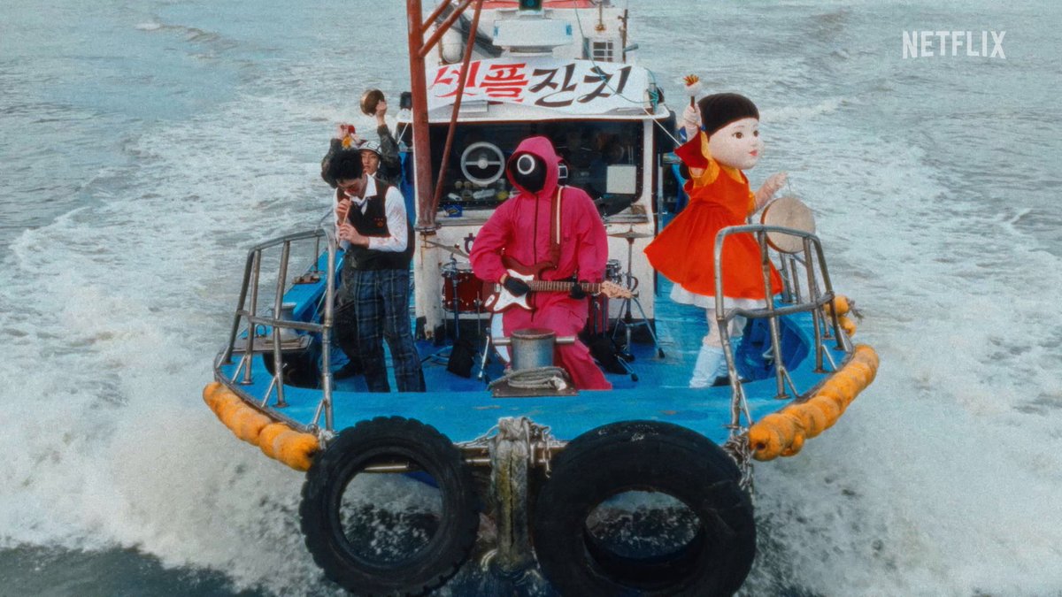 A scene from a Netflix production showing three figures performing music on a small boat moving through choppy waters, with Korean text '달짝지근한' on the boat.