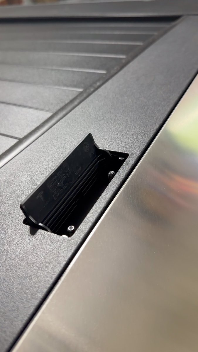 A small black plastic clip or mount is attached to the textured metal surface of what appears to be a laptop or device casing.