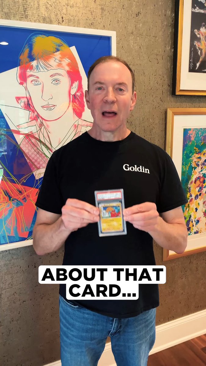 A man in a black "Goldin" t-shirt holds up a PSA-graded Pokemon card while standing in front of framed artwork, with the caption "ABOUT THAT CARD..." overlaid. The image promotes the Goldin auction featuring the 2015 Pokemon Japanese XY Promo Art Academy Pikachu card graded PSA Gem Mint 10.