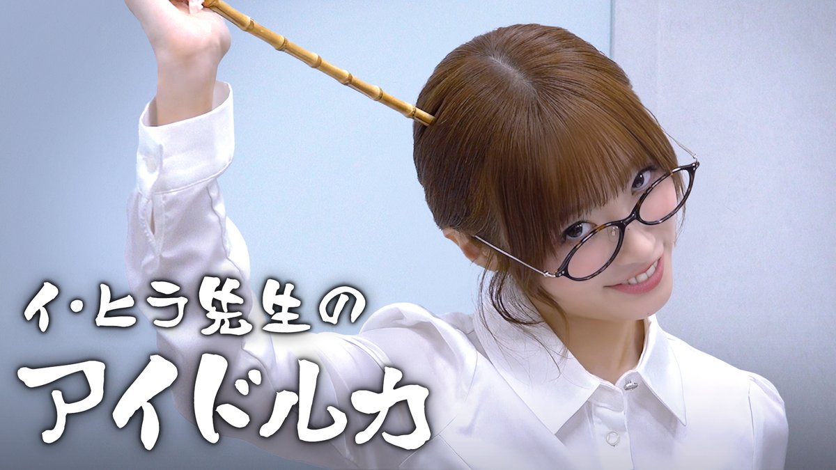 The post's title in Japanese text reads "イ・ヒラ先生のアイドル力" (Lee Hee-ra's Idol Power), which introduces the video as a feature on Lee Hee-ra, a top idol instructor. However, the image shows a smiling woman with brown hair in a half-up style, wearing round tortoiseshell glasses and a white button-up shirt, holding up what appears to be a bamboo pointer stick—likely a teaser image of the instructor herself discussed in the YouTube video about the importance of vision for idols.