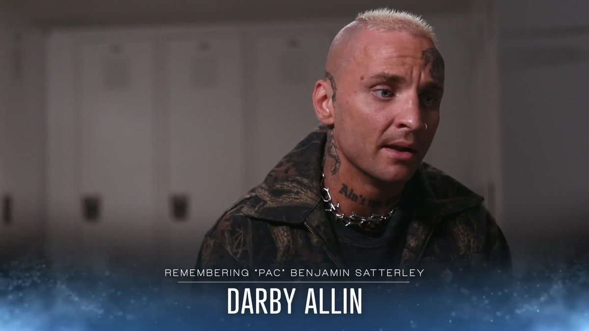 A man with bleached blonde hair and face tattoos, wearing a spiked chain necklace and camouflage jacket, speaks emotionally against a backdrop of lockers. Text at the bottom reads "REMEMBERING 'PAC' BENJAMIN SATTERLEY" and "DARBY ALLIN," identifying the scene as AEW wrestler Darby Allin paying tribute to his late friend and fellow wrestler Benjamin "Pac" Satterley, matching the post's heartfelt memorial tone.