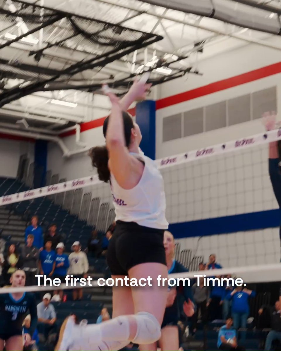 A female volleyball player in a white jersey jumps to spike the ball at the net in an indoor court, with the text 'The first contact from Timme.' overlaid at the bottom.