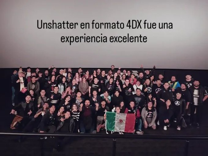 A group photo of people posing in front of a screen that reads 'Unshatter en formato 4DX fue una experiencia excelente', with a Mexican flag visible in the front row.