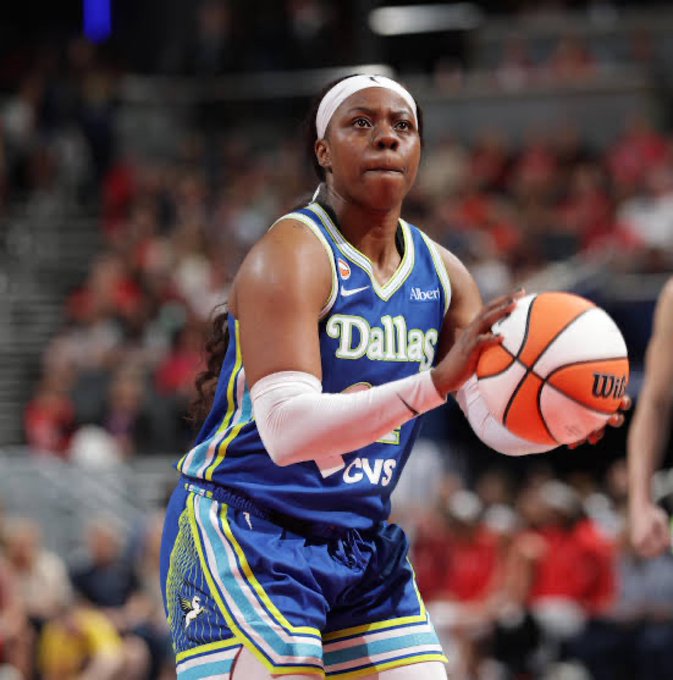 A Dallas Wings WNBA player wearing a blue jersey with 'Dallas' and 'CVS' logos holds a Wilson basketball during a game.