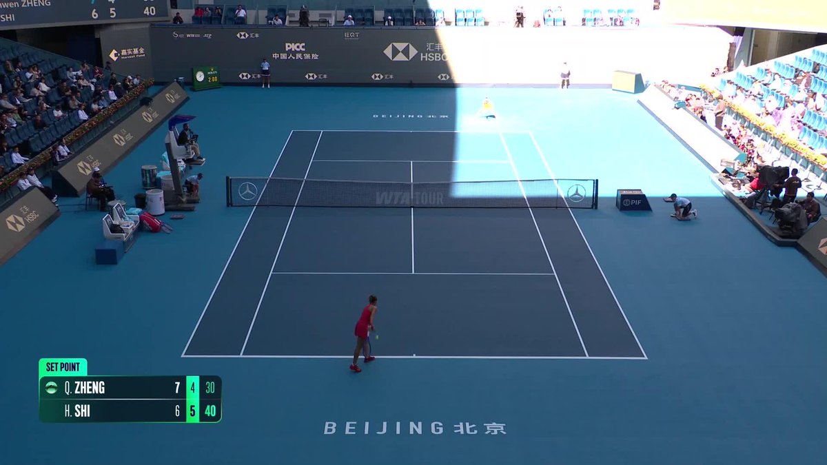 A tennis match on a blue court in Beijing featuring Q. Zheng vs H. Shi, with the scoreboard showing Q. Zheng 7 4 30 and H. Shi 6 5 40 at SET POINT, with the player serving in red.