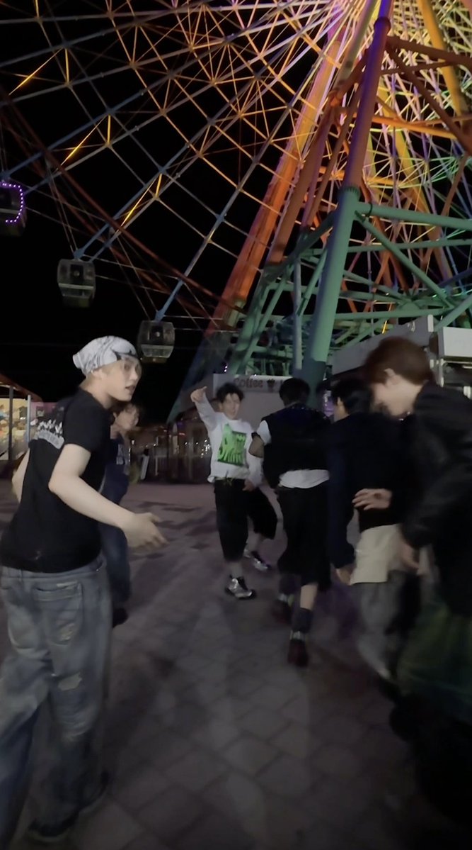 A group of energetic young men dance and pose excitedly at night beneath a brightly lit Ferris wheel at an amusement park, with motion blur capturing their lively movements. The image's vibrant, celebratory mood matches the post's announcement of KickFlip's new mini album "KICK OFF THE WALL Pt. 1," releasing October 6, 2026.